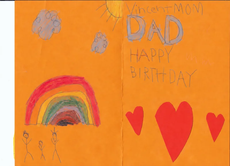 A handmade birthday card on orange paper with a rainbow, three people, red paper hearts, and handwritten birthday wishes for Dad
